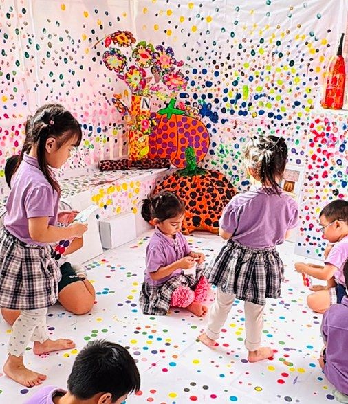 Children creating colourful polka-dot artwork together in an immersive art installation