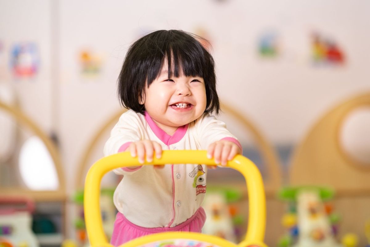 An infant playing happily on a ride-on toy in the Cherie Hearts infant care nursery